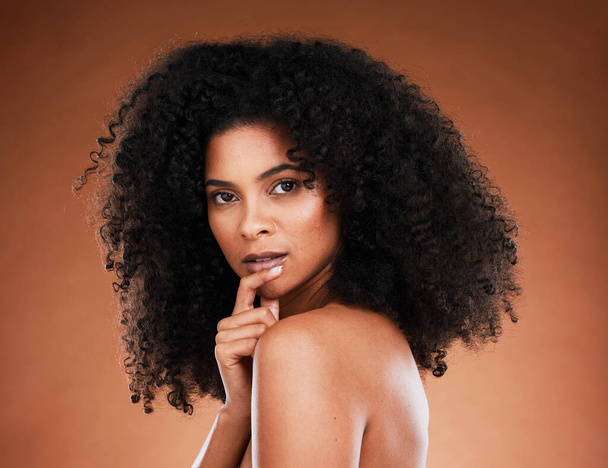 Beauty, makeup and portrait of a black woman with an afro against a brown studio background. Skincare, wellness and face of an African cosmetics model with a glow on body from luxury cosmetology. - Fotoğraf, Görsel
