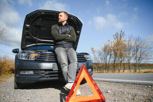 A young man with a black car that broke down on the road,copy space - Foto, afbeelding