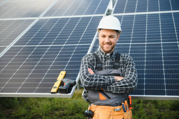 Expert is inspecting quality of a solar batterys. Worker in uniform and helmet with equipment. Ecology power conservation concept - Foto, Bild