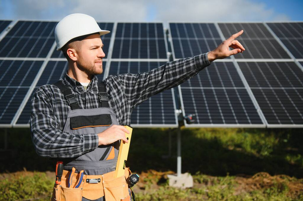 Male worker in uniform outdoors with solar batteries at sunny day - Foto, Imagem
