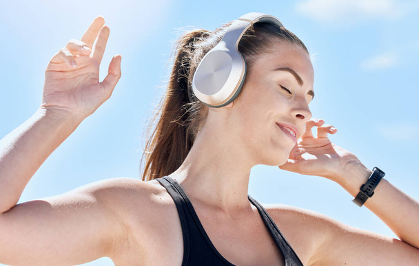 Music, summer and dance with a woman outdoor in nature against a blue sky for dancing or freedom. Radio, relax and carefree with an attractive young female streaming or listening to audio outside. - Фото, изображение