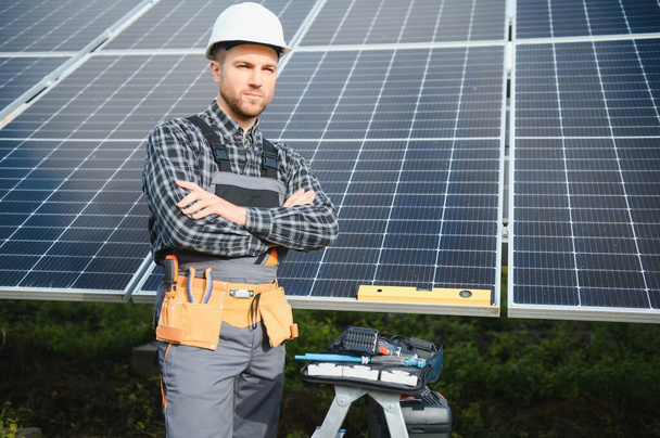 Expert is inspecting quality of a solar batterys. Worker in uniform and helmet with equipment. Ecology power conservation concept - Photo, image