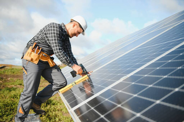Worker installing solar panels outdoors. - Photo, image
