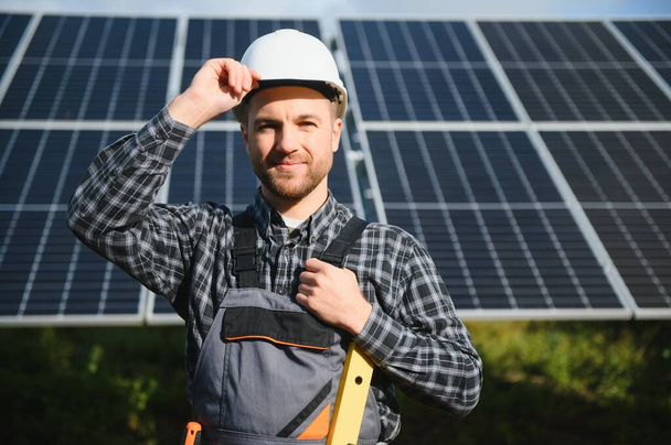 Expert is inspecting quality of a solar batterys. Worker in uniform and helmet with equipment. Ecology power conservation concept - Foto, immagini