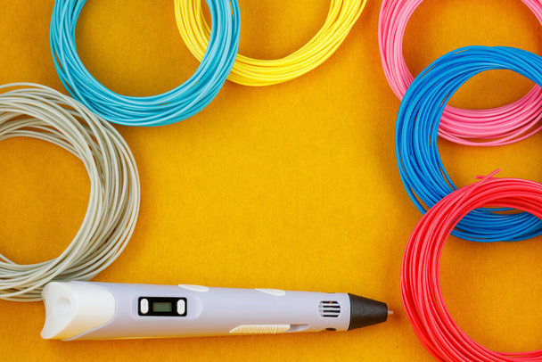 3d pen, and kit of colourful PLA or ABS plastic filament on yellow background. Closeup - Foto, afbeelding