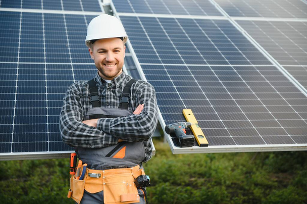 A handyman standing on the rooftop with solar panels and smiling at the camera - Foto, afbeelding