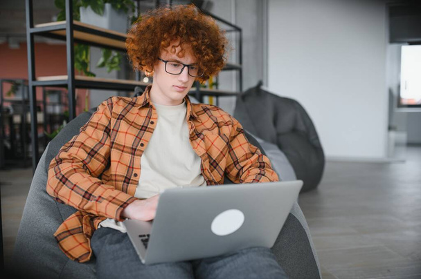 Προσεκτικός τύπος ελεύθερος επαγγελματίας σε casual ρούχα περιήγηση laptop, ενώ εργάζονται σε έργο στη βεράντα του καφέ κατά τη διάρκεια της ημέρας - Φωτογραφία, εικόνα