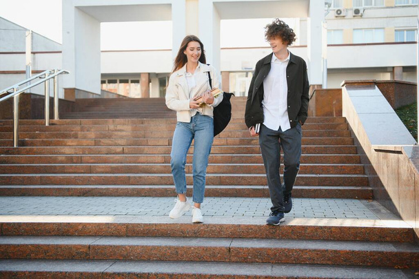 Front view of two students walking and talking in an university campus - Foto, imagen