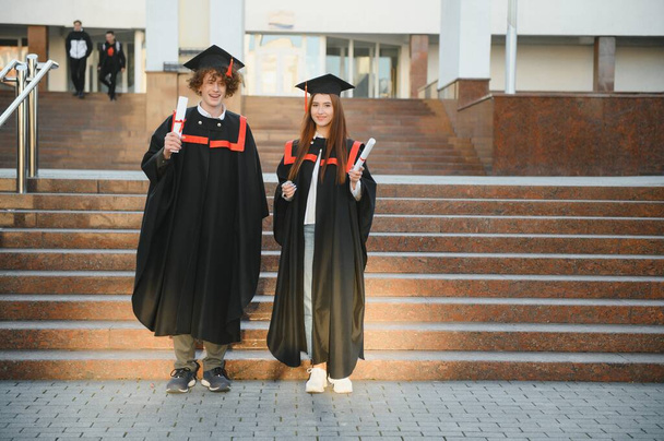 Portrait of two happy graduating students - Фото, изображение
