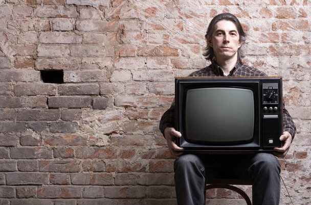 Чоловік тримає ретро телевізор
 - Фото, зображення
