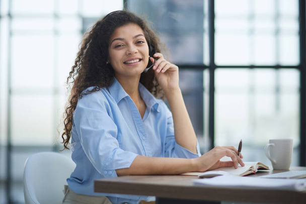 Portrait of an attractive cheerful experienced girl advising clients on customer service in the office - Foto, Bild