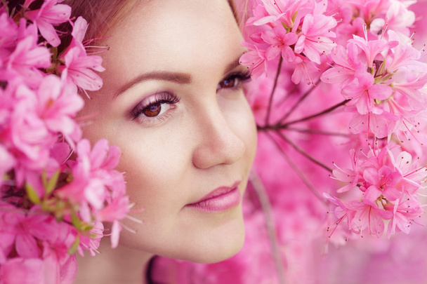 Крупним планом портрет красивої молодої жінки в рожевому пухнастому весняному квітковому кущі
 - Фото, зображення