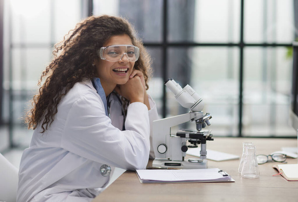Young woman in biological laboratory. Attractive young female scientis. Scientist using a microscope in a laboratory - Foto, Bild