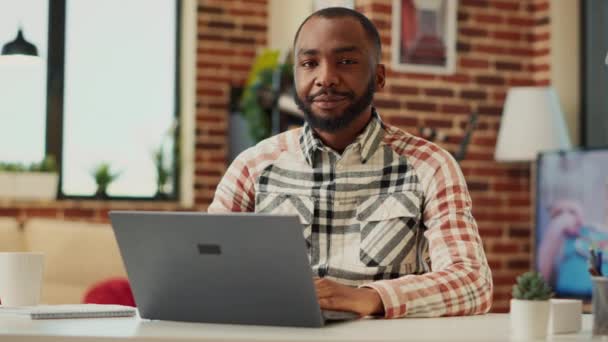 Une personne afro-américaine travaillant à distance de chez elle, utilisant un ordinateur portable et écrivant un rapport d'affaires sur un réseau de vente. Homme freelance apprentissage en ligne dans l'appartement, enseignement de la comptabilité. Coup de main. - Séquence, vidéo