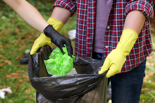 Man and woman with plastic bag collecting garbage in park, closeup - Foto, immagini