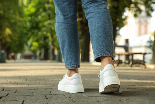 Woman in stylish sneakers walking on city street, closeup - 写真・画像