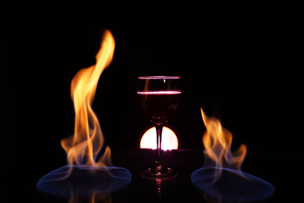 verre de vin rouge sur la table avec le feu dans l'art de fond - Photo, image