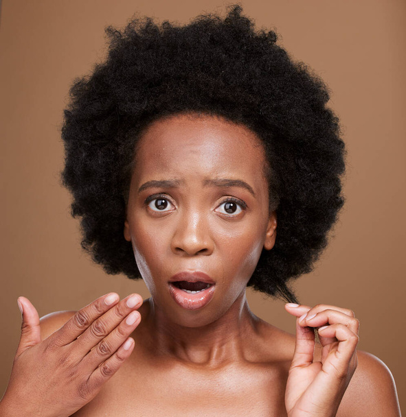 Hair, portrait and black woman in studio for problem, hair loss and hair care against a brown background. Face, model and afro hairstyle fail by woman confused, shocked and surprised by damaged hair. - Photo, Image
