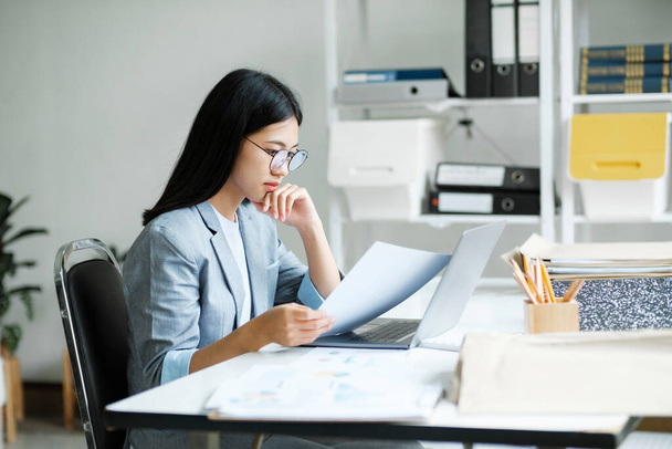 Молодая азиатская бизнес-женщина онлайн работает на ноутбуке в домашнем офисе. Молодая девушка азиатский студент или удаленный учитель с помощью компьютера онлайн обучение, виртуальное обучение, смотреть онлайн-вебинар образования на - Фото, изображение
