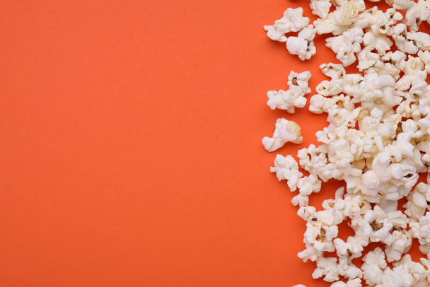Tasty popcorn scattered on orange background, flat lay. Space for text - Foto, Imagem