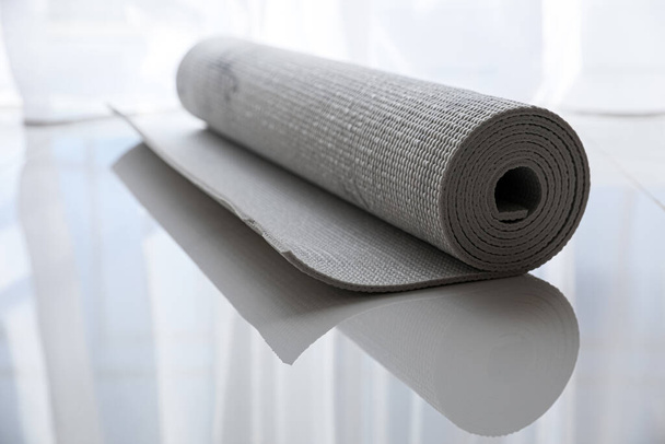 Rolled karemat or fitness mat on tiled floor - 写真・画像