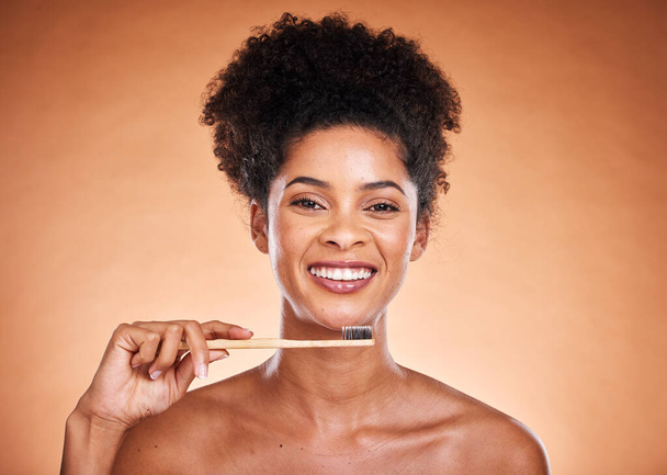 Dental care, toothbrush and hygiene with a model black woman brushing her teeth in studio on a beige background. Portrait, face and oral treatment with an attractive young female proud of her routine. - 写真・画像