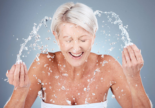 Volwassen vrouw, water spatten of wassen gezicht in huidverzorging routine, 's morgens hygiëne onderhoud of gezondheid wellness. Glimlach, gelukkig of bejaard schoonheidsmodel in gezichtsreiniging en natte waterdruppel. - Foto, afbeelding