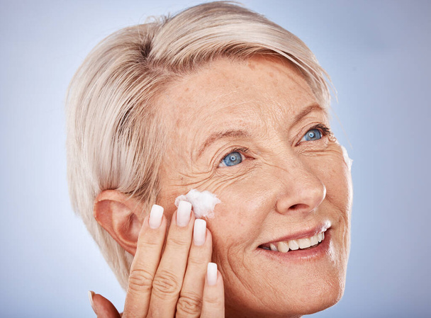 Skincare, thinking and senior woman with cream for face against a grey studio background. Sunscreen, happy and elderly model with an idea with a facial dermatology product for beauty and self care. - Fotoğraf, Görsel