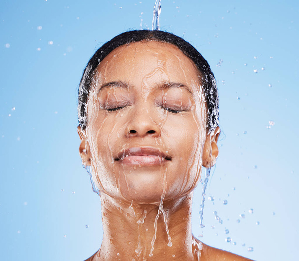 Жінка, душ і вода в гідратації обличчя для свіжої чистої гігієни на фоні синьої студії. Жінка в охороні здоров'я для миття посуду, очищення та оздоровлення або лікування природними очищеннями
. - Фото, зображення