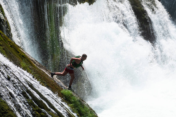 Молодой человек прыгает в воду чистой реки на водопаде, плавает, любит проводить время на летних каникулах. Высокое качество фото - Фото, изображение