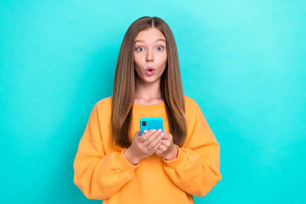 Photo of young excited funny teen girl pouted lips hold phone unexpected how popular her new tiktok video isolated on aquamarine color background. - Foto, Imagem