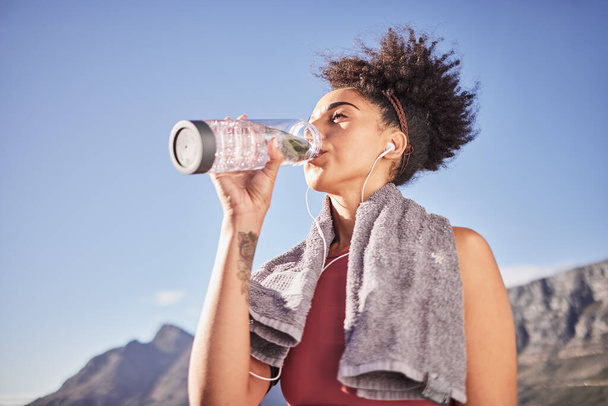 Music, drinking water and woman in nature for fitness, training and morning cardio run along mountain with mockup. Podcast, water and black woman relax after running with radio, wellness and track. - Photo, image