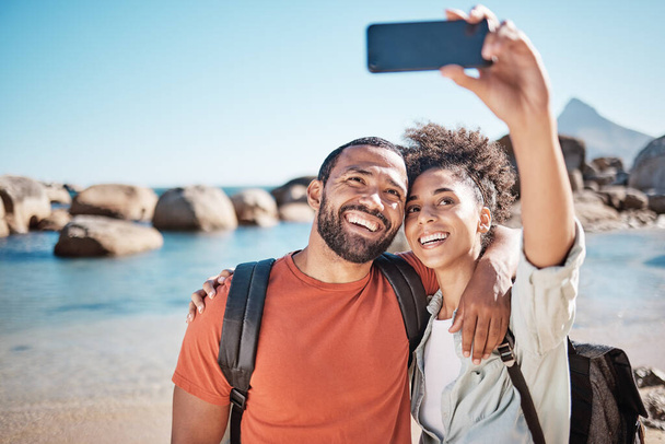 Para, miłość i telefon selfie na plaży na podróż przygoda lub letnie wakacje. Szczęśliwy mężczyzna, kobieta uśmiech i fotografia na wakacje styl życia na 5g smartphone dla mediów społecznościowych w oceanie wody na zewnątrz. - Zdjęcie, obraz