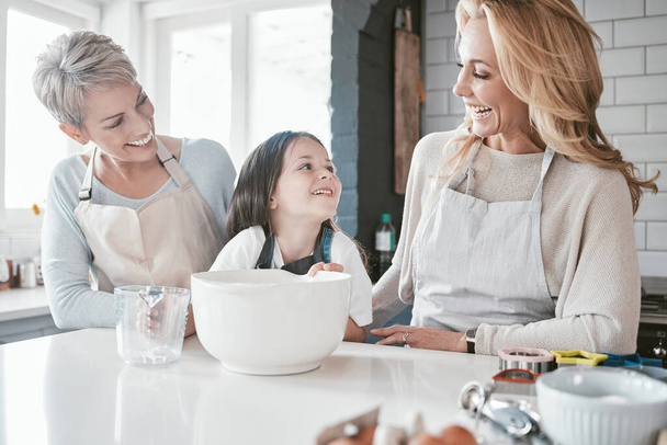 .Child, grandmother and mom teaching cooking together in kitchen bonding, quality time or fun activity at home. Happy mother, grandma and excited kid chef learning to bake cake with family support - Photo, Image