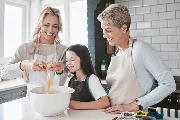 Mom, grandmother and kid baking together in kitchen, family home and house of fun, learning or development. Happy family generation, girl and child crack eggs for dessert, cookies and teaching recipe. - Photo, Image