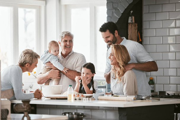 Big family, love and cooking in home kitchen, bonding or having fun. Support, care and grandparents, father and mother, baby and girl baking, learning and talking while enjoying quality time together. - 写真・画像