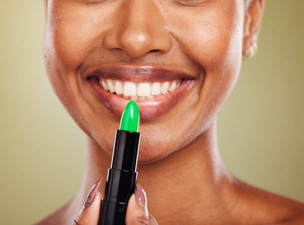 Green lipstick, mouth and lips with black woman and beauty closeup, lip care and cosmetic product against studio background. Face, makeup and wellness with glowing skin and natural cosmetics smile - Φωτογραφία, εικόνα