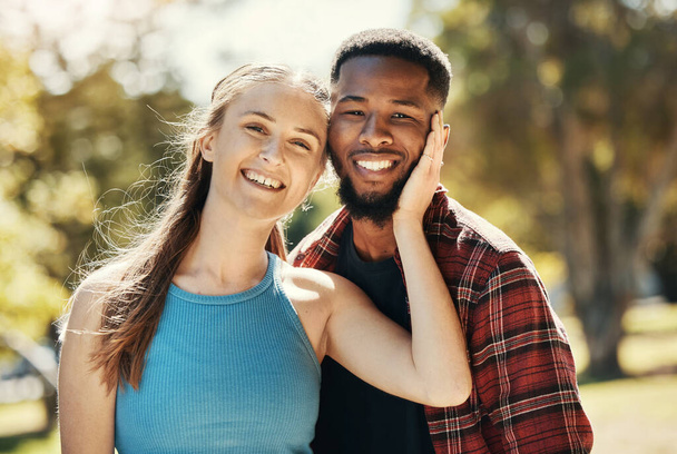Portrait of interracial couple, young people and relax in park, sunshine and summer for love, care or quality time together. Happy man, smile woman and diversity date in nature, outdoor and happiness. - Φωτογραφία, εικόνα