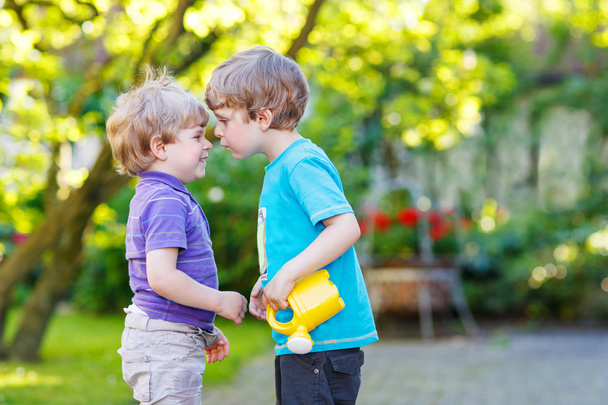 Two little sibling boys hugging and having fun outdoors - Photo, Image