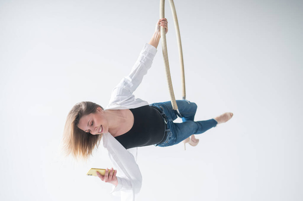 Biała gimnastyczka wykonuje ćwiczenia aerobiku i używa smartfona - Zdjęcie, obraz