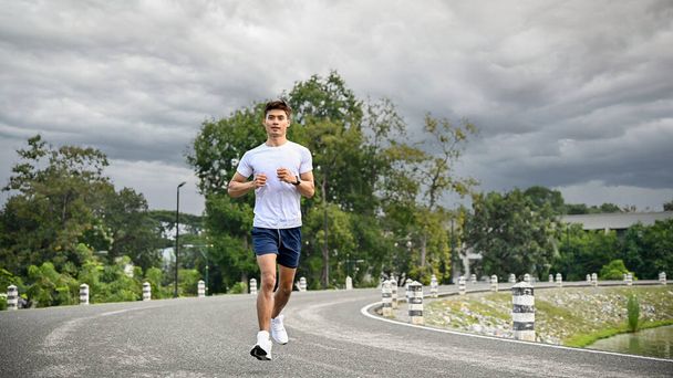 Atletico e sano giovane asiatico in abbigliamento sportivo e scarpe da corsa professionali che corrono all'aperto. Stile di vita sano concetto - Foto, immagini