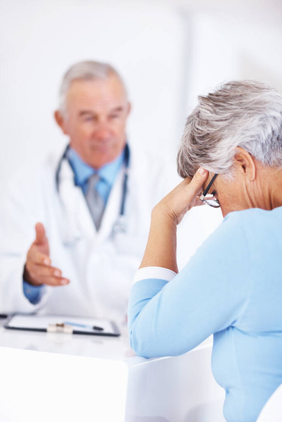 Unhappy patient with doctor. Mature doctor discussing medical report with unhappy patient - 写真・画像