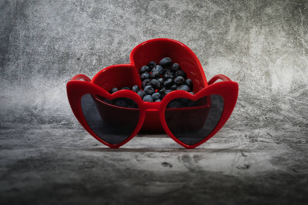 rotes herzförmiges Gericht mit Blaubeeren und roten Herztönen - Foto, Bild