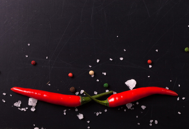 Red hot chilli pepper with sea salt and colored pepper on black  - Фото, изображение