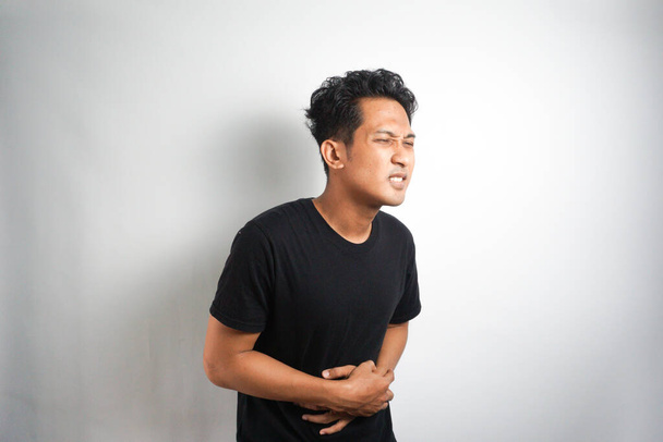 Мужчина азиатской внешности, страдающий от боли в животе на фоне проблем со здоровьем - Фото, изображение