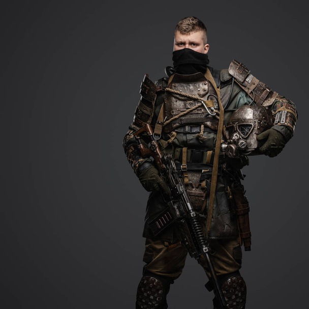 Studio shot of isolated on grey background military man dressed in armor holding shotgun. - Photo, Image