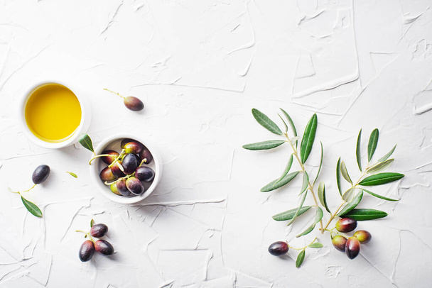 Olive oil in bowl with fresh olives fruit and olive branch on white background - Foto, Imagem