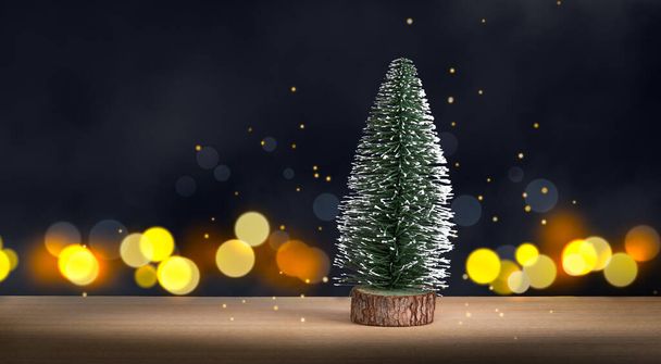 Pequeño árbol de Navidad en madera, contra oscuras luces desenfocadas fondo. - Foto, imagen