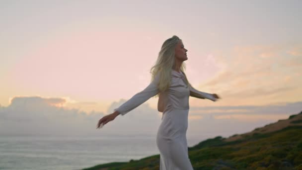 Slim lady whirling sea view cliff closeup. Cute woman spinning around enjoying marine vacation. Calm girl posing at sunset evening outdoors. Positive model feeling happy at ocean landscape alone - Footage, Video
