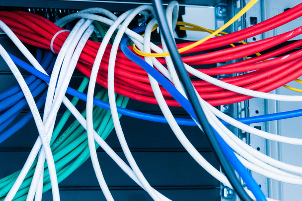 куча патч сетевых кабелей, отсортированных в стойке шкафа, ведущих от патч-панели в серверной в комнате центра обработки данных - Фото, изображение